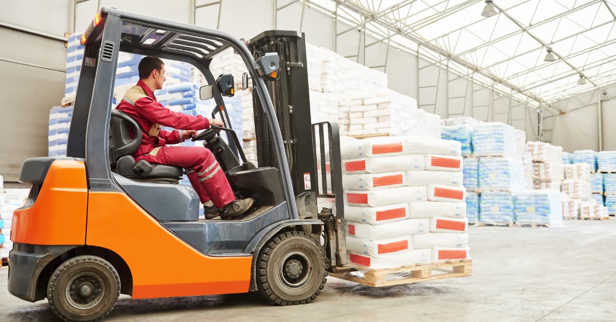 Carretilla elevadora transportando un palé de mercancía en el interior de un almacén logístico